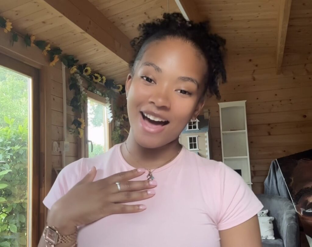 A young woman smiling and looking at the camera. She has black hair in a ponytail.